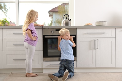 Little kids baking something in oven at home