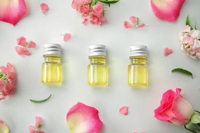 Flat lay composition with essential oils and flowers on light background