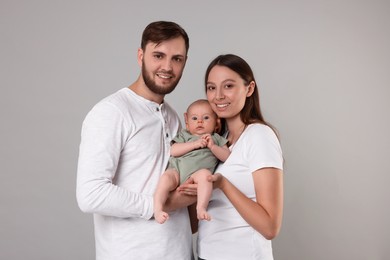Photo of Happy family. Parents with their cute baby on grey background