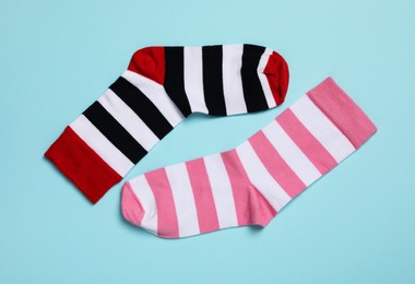 Photo of Different stiped socks on light blue background, flat lay