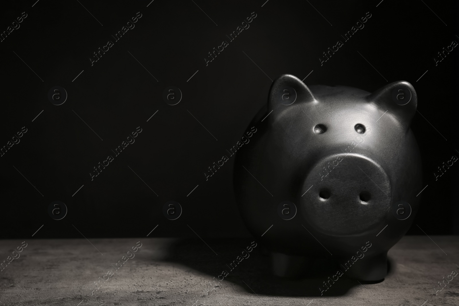 Photo of Black piggy bank on table against dark background with space for text. Poverty concept