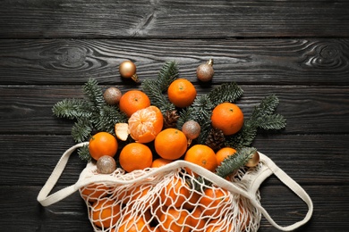 Flat lay Christmas composition with fresh tangerines in mesh bag on dark wooden table