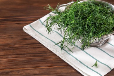 Photo of Colander with fresh tarragon leaves on wooden table. Space for text