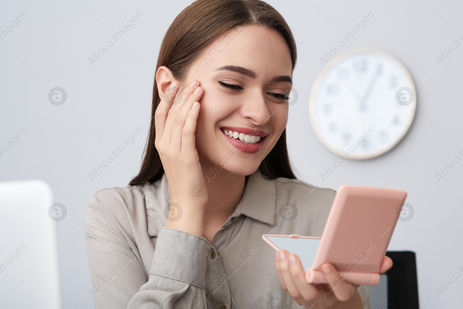 Photo of Young woman looking at herself in cosmetic pocket mirror indoors