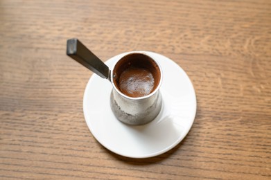 Photo of Jezve with fresh coffee on wooden table, above view