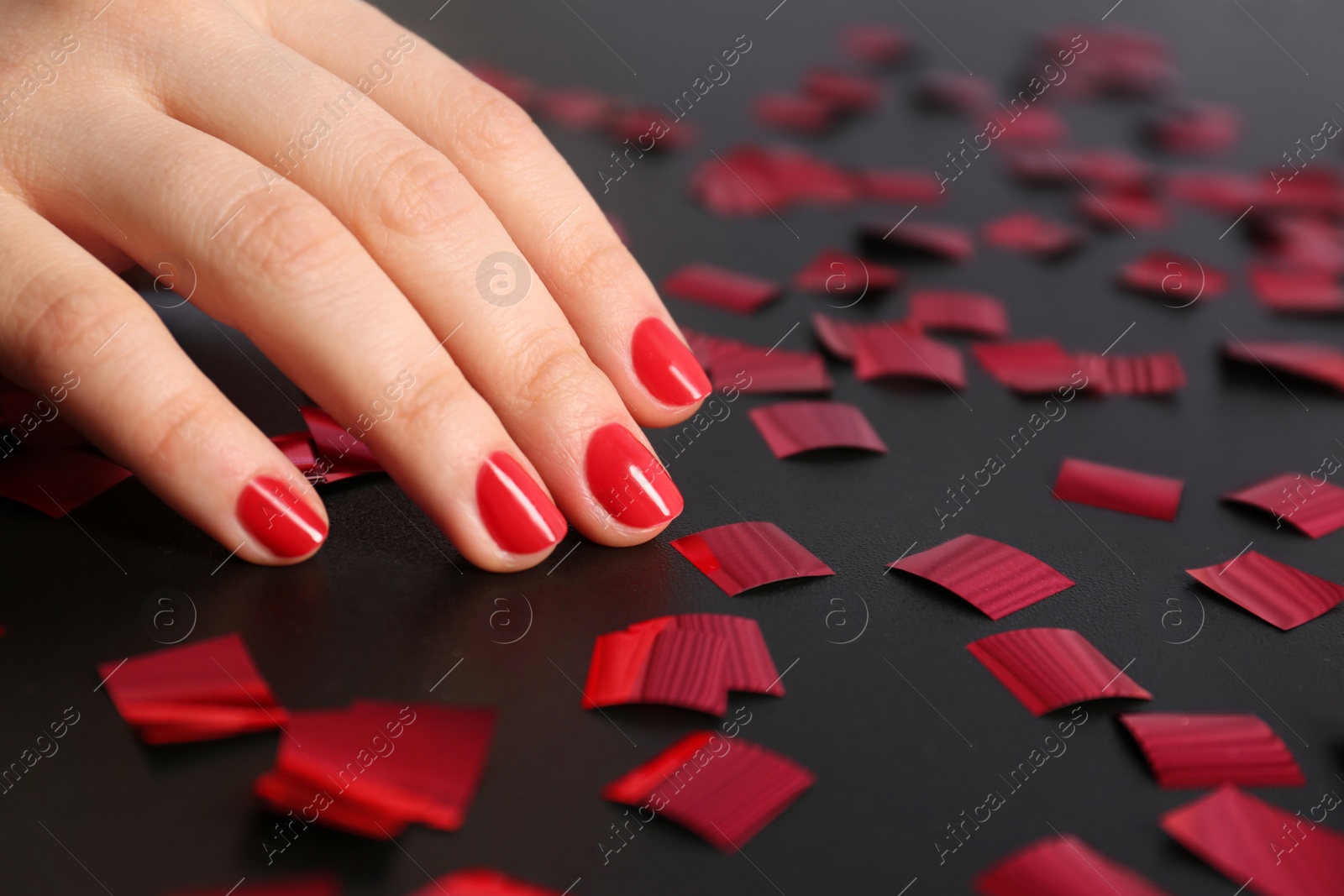 Photo of Woman showing red manicure on dark background, closeup with space for text. Nail polish trends