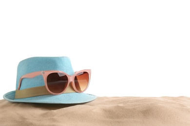 Composition with hat, beach sand and sunglasses on white background, space for text