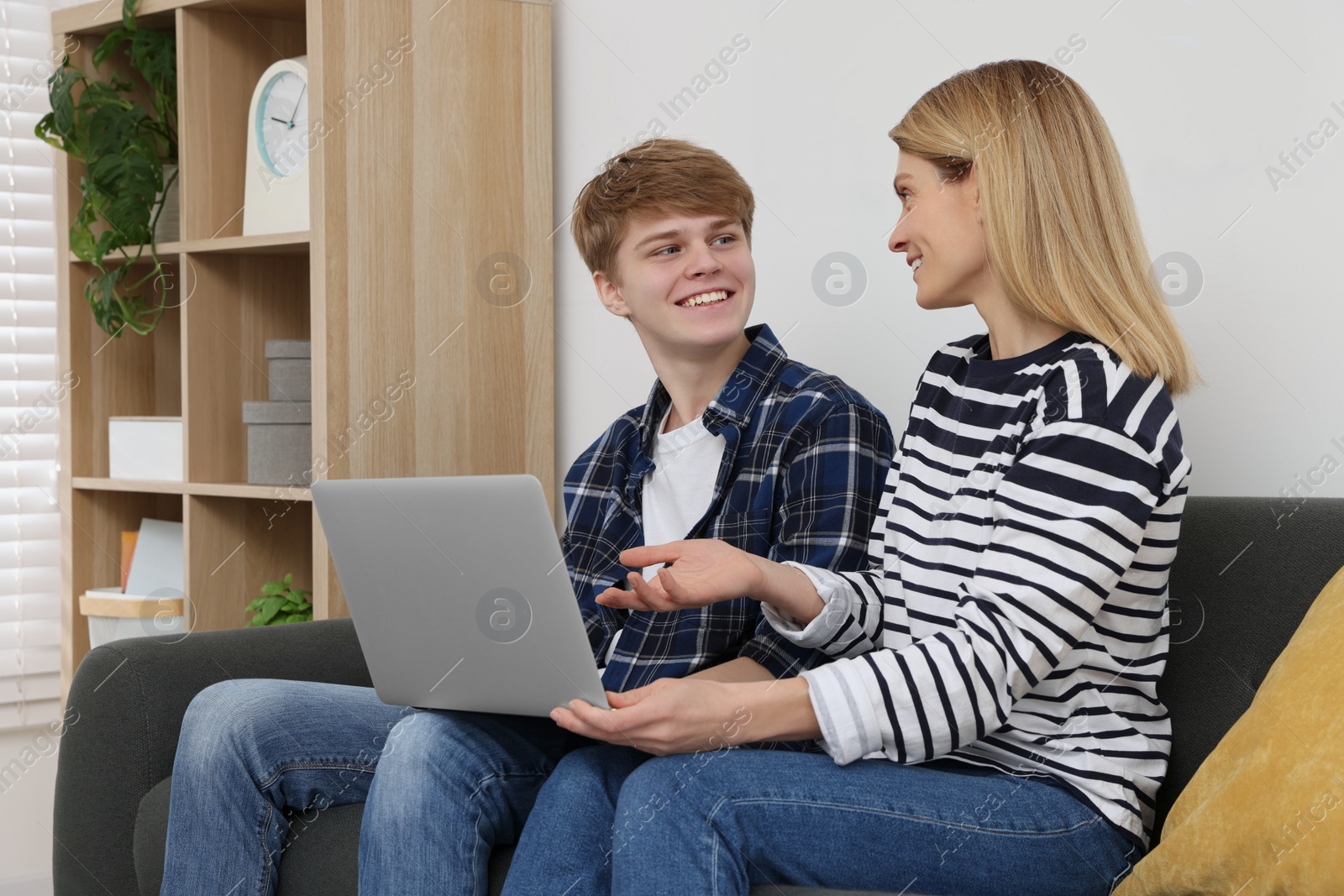 Photo of Happy mother and her teenage son with laptop at home