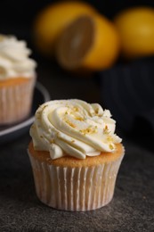 Photo of Delicious cupcake with white cream and lemon zest on gray table, closeup