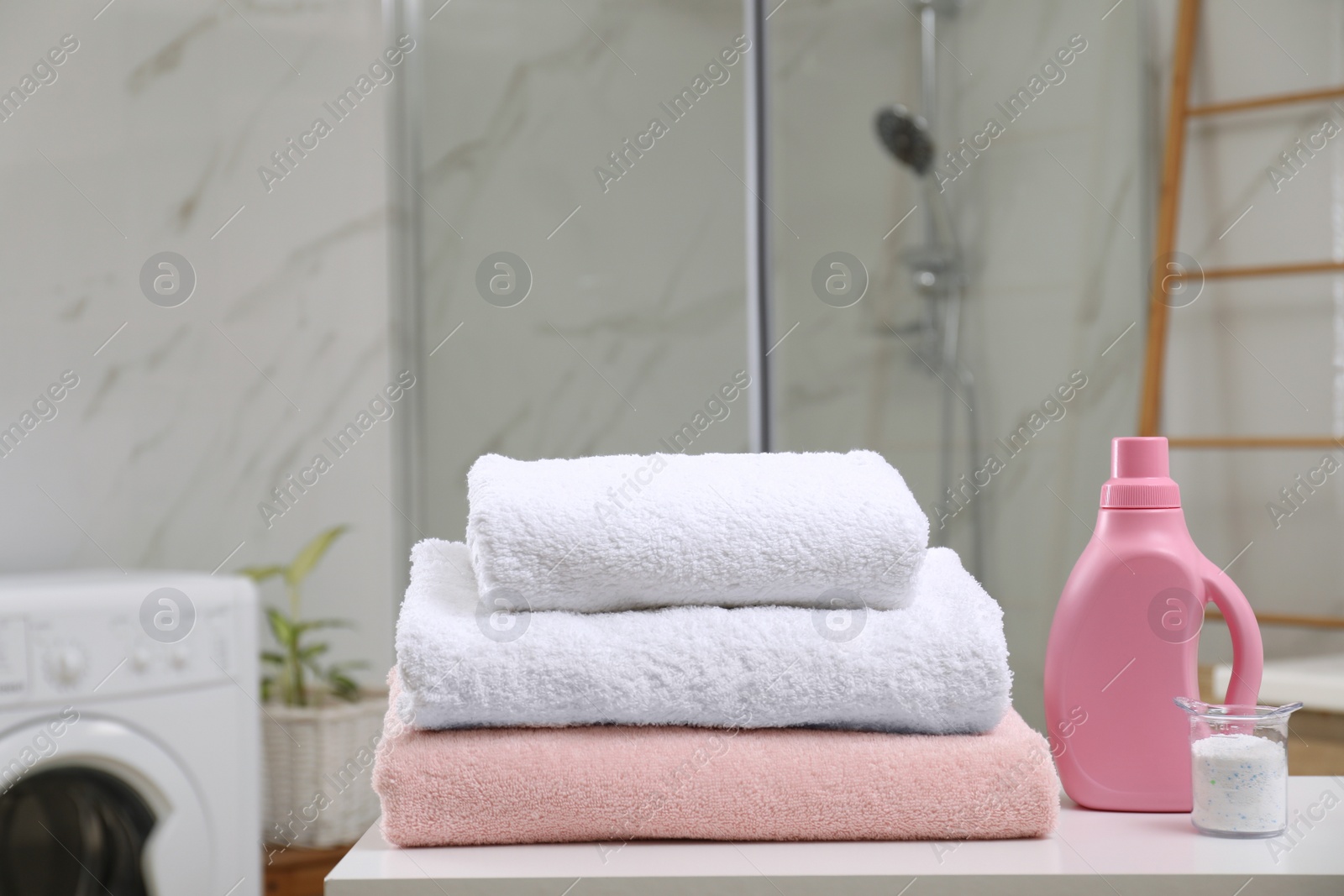 Photo of Clean towels and detergents on table in laundry room