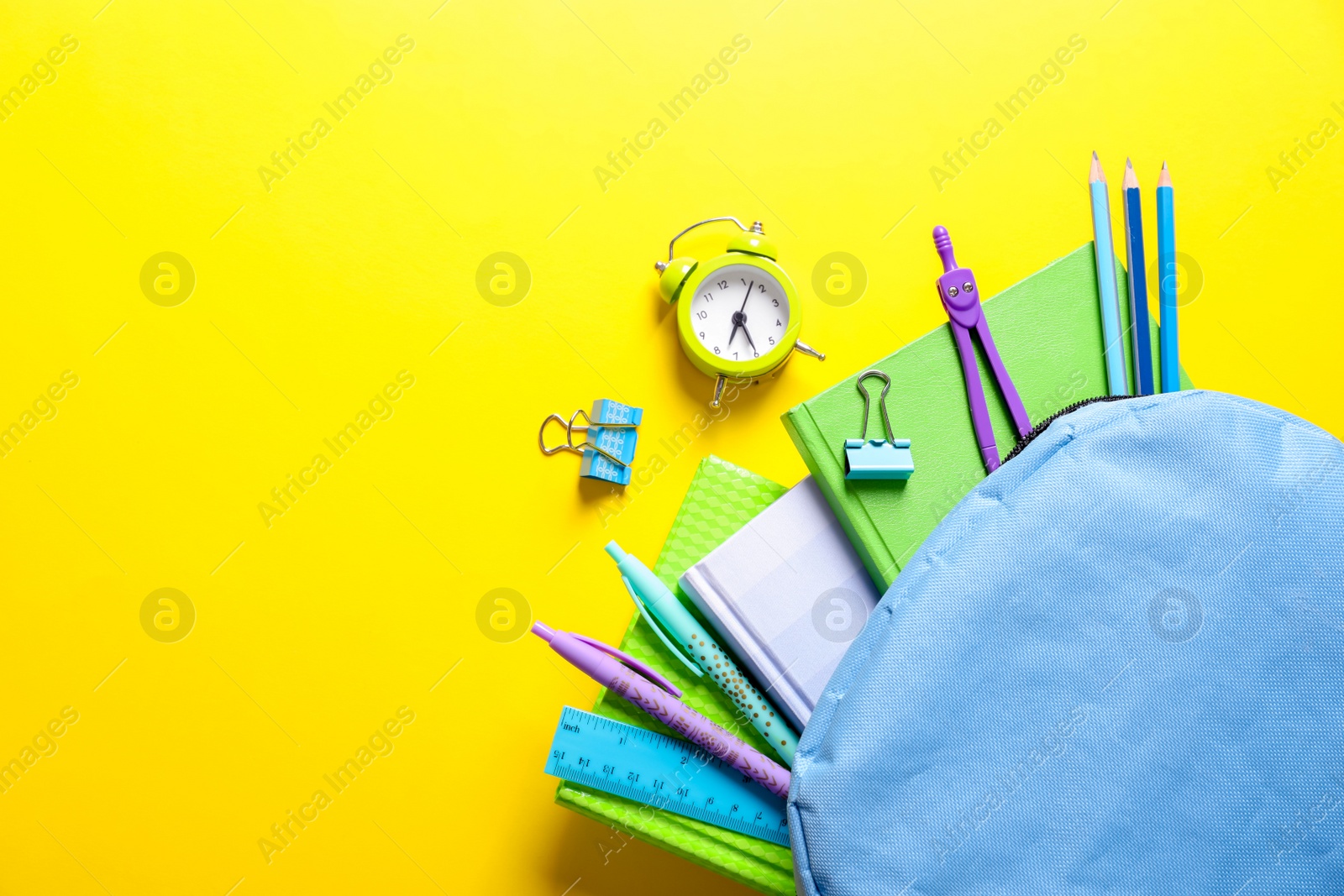 Photo of Flat lay composition with backpack and school stationery on color background