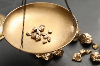 Photo of Vintage scales with gold nuggets on black table, closeup