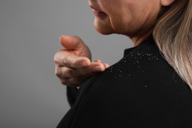 Photo of Woman brushing dandruff off her sweater on gray background, closeup