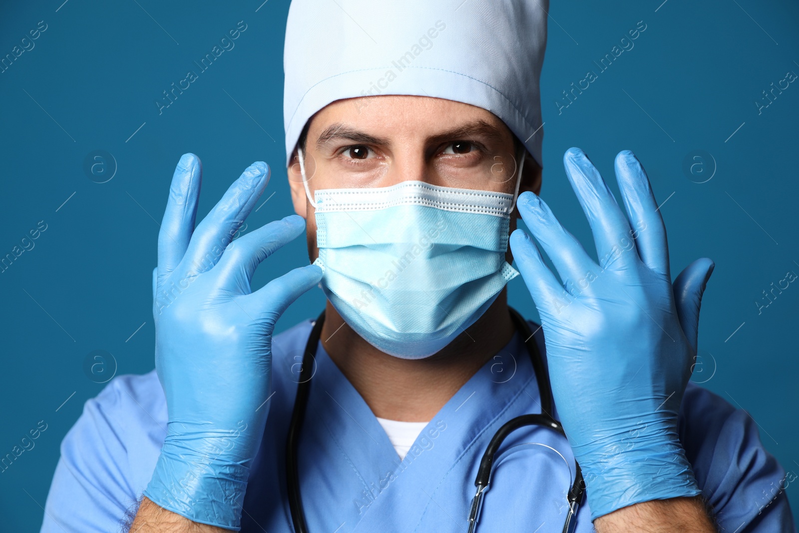 Photo of Doctor in protective mask and medical gloves against blue background