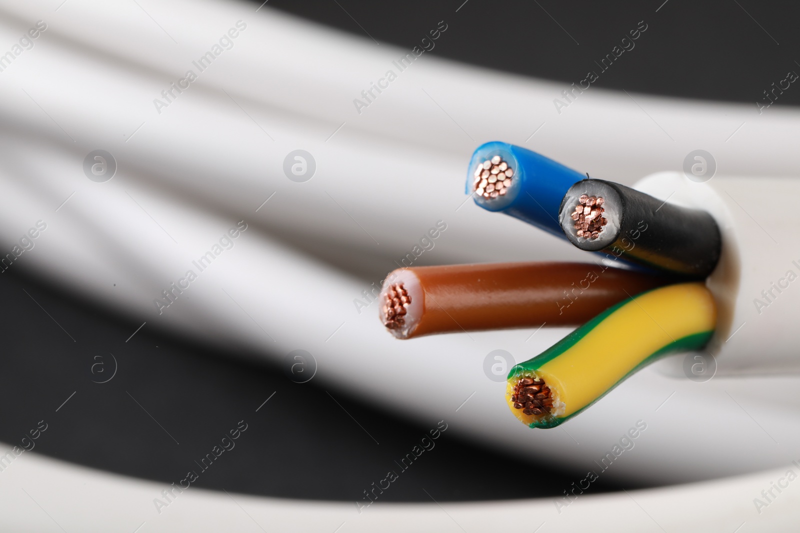 Photo of New colorful electrical wire on blurred background, closeup. Space for text