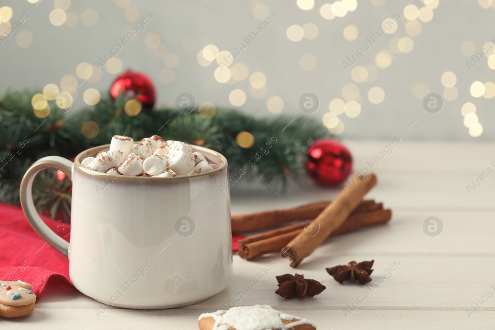 Photo of Delicious hot chocolate with marshmallows and Christmas decor on white wooden table, space for text