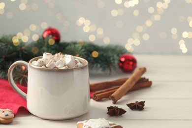 Photo of Delicious hot chocolate with marshmallows and Christmas decor on white wooden table, space for text