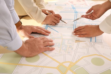 Photo of Professional cartographers working with cadastral map at table, closeup