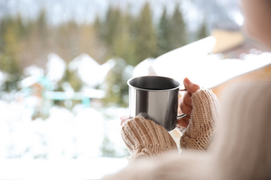 Photo of Woman with cup of tasty coffee outdoors on winter morning, closeup