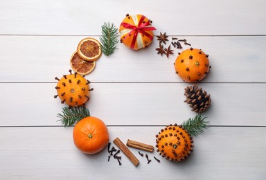 Pomander balls made of tangerines with cloves, spices and fir branches on white wooden table, flat lay. Space for text