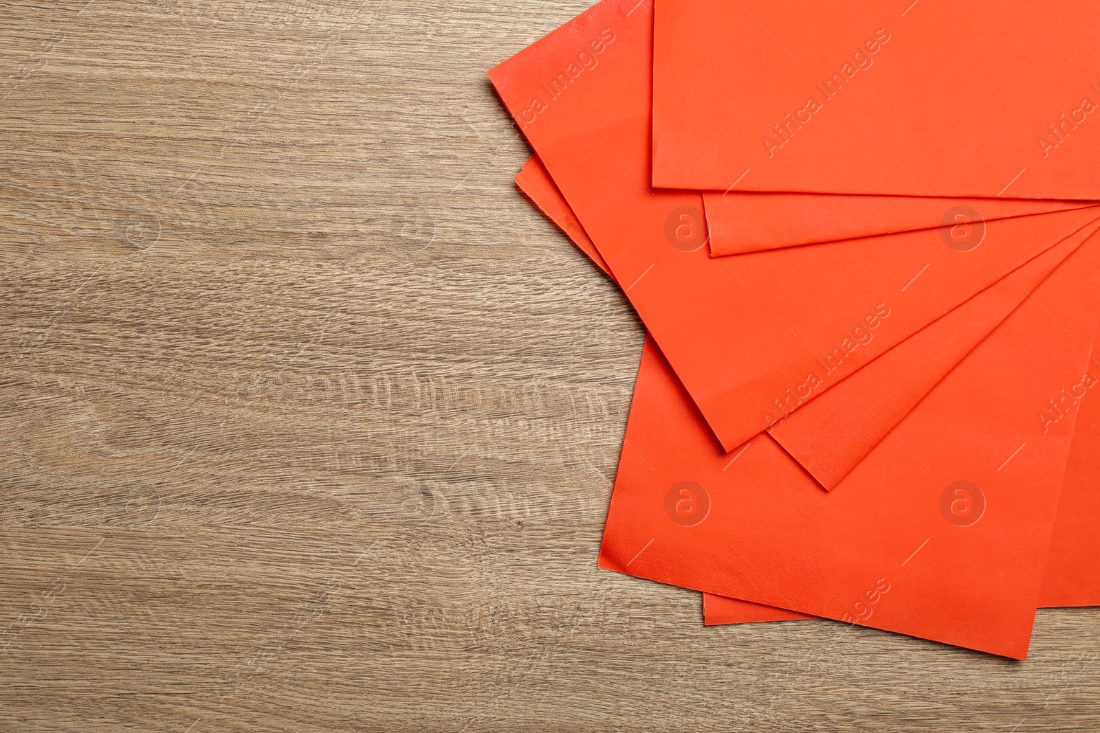 Photo of Red reusable beeswax food wraps on wooden table, top view. Space for text