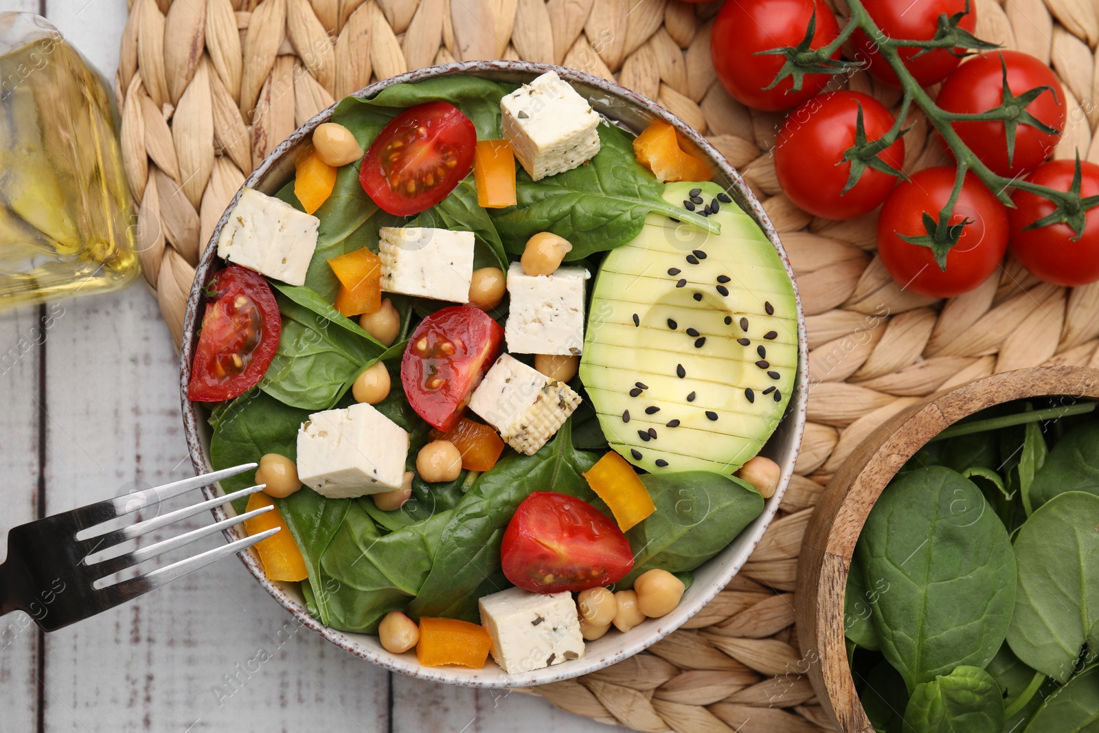 Photo of Bowl of tasty salad with tofu and vegetables on white wooden table, flat lay