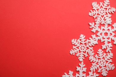 Photo of Beautiful decorative snowflakes on red background, flat lay. Space for text