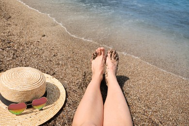 Woman with straw hat and heart shaped sunglasses on sea beach, closeup