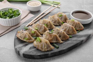 Delicious gyoza (asian dumplings) with green onions, soy sauce and chopsticks on light gray table