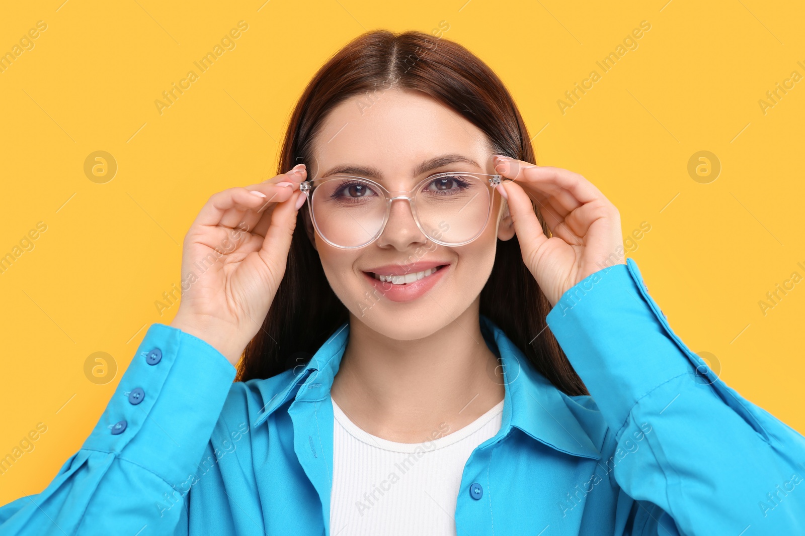 Photo of Portrait of smiling woman in stylish eyeglasses on orange background