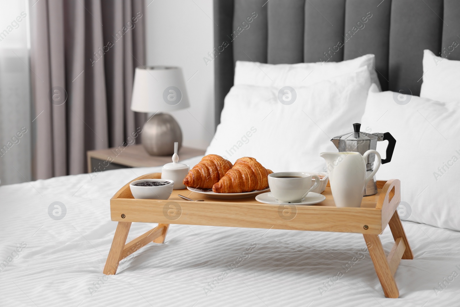 Wooden tray with tasty breakfast on bed at home Photo of Wooden tray with tasty breakfast on bed at home