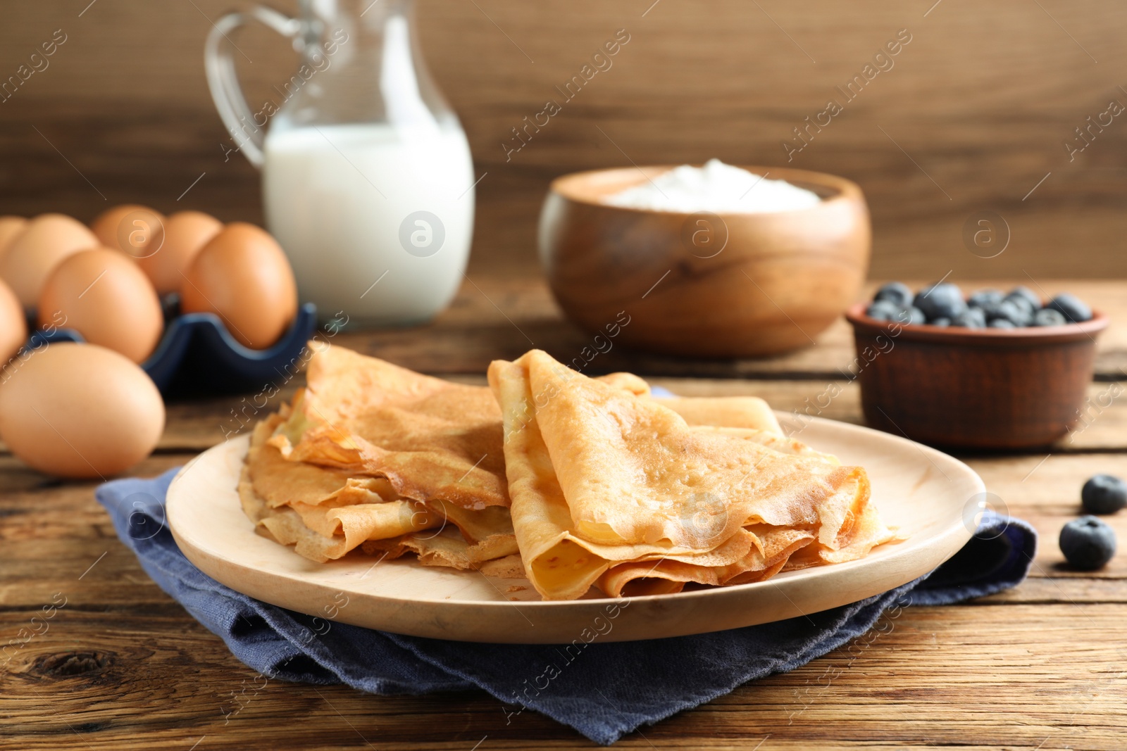 Photo of Delicious crepes served on wooden table. Space for text