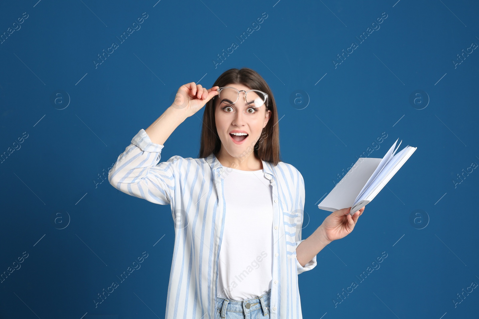 Photo of Emotional young woman with book on blue background