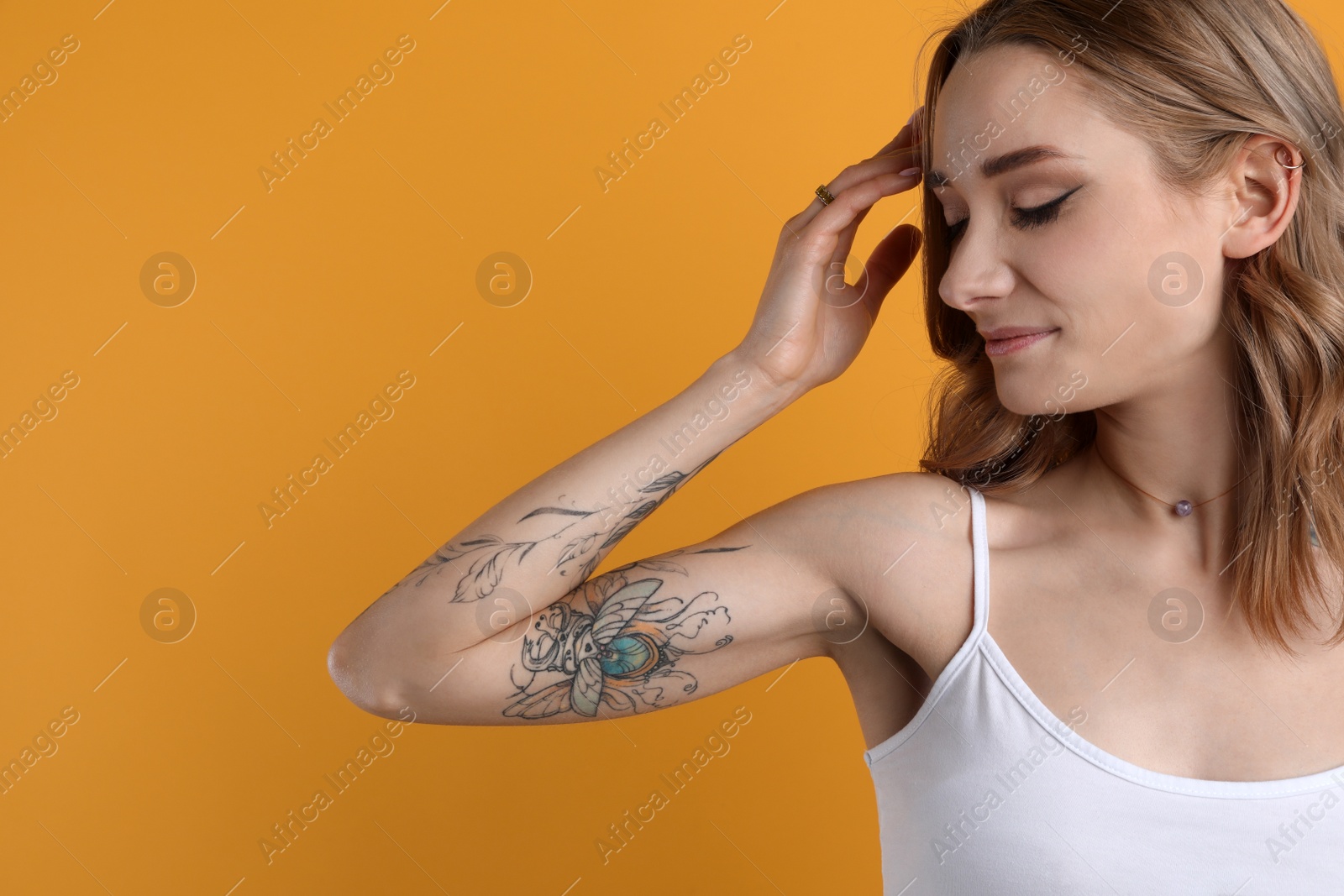 Photo of Beautiful woman with tattoos on arm against yellow background