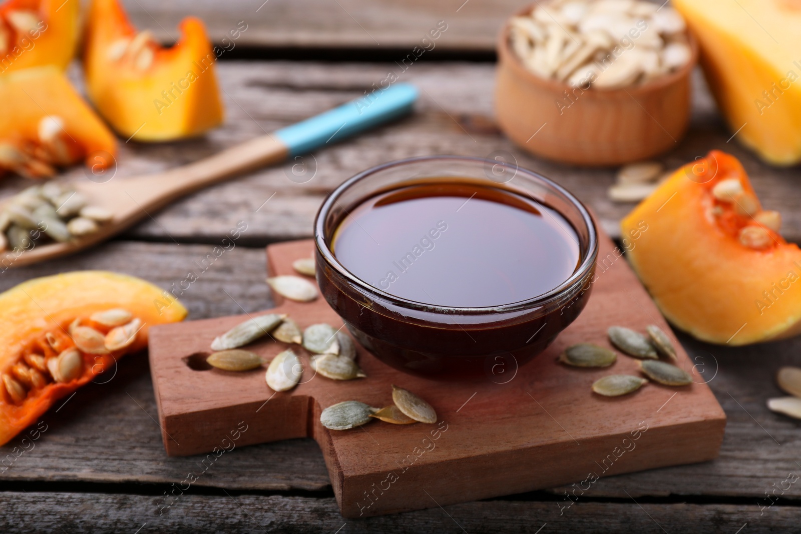 Photo of Fresh pumpkin seed oil in glass bowl on wooden table