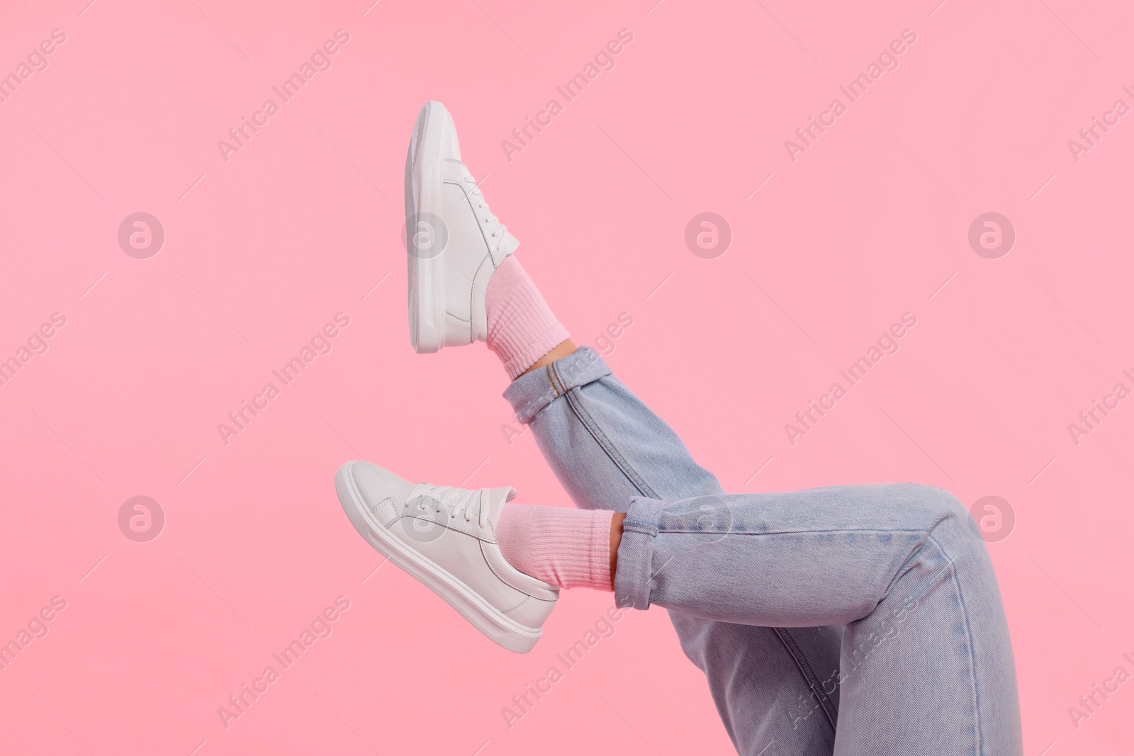 Photo of Woman wearing stylish white sneakers on pink background, closeup. Space for text