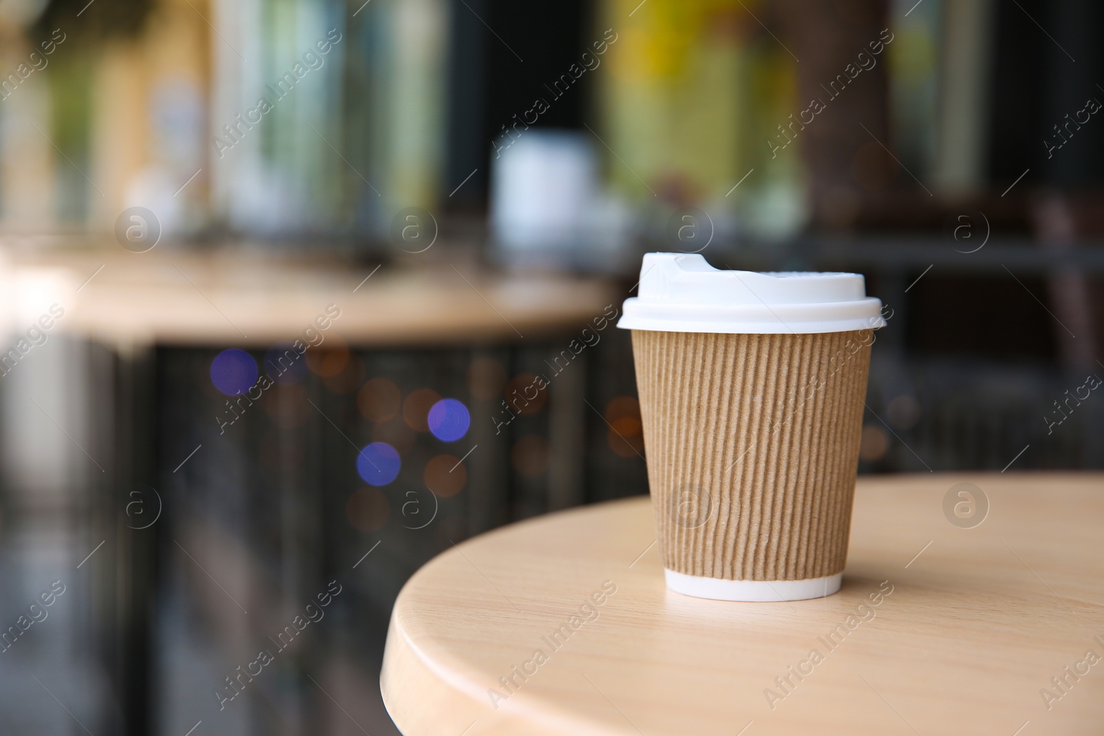 Photo of Takeaway paper coffee cup on table outdoors. Space for text