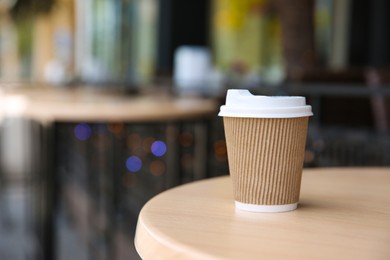 Photo of Takeaway paper coffee cup on table outdoors. Space for text