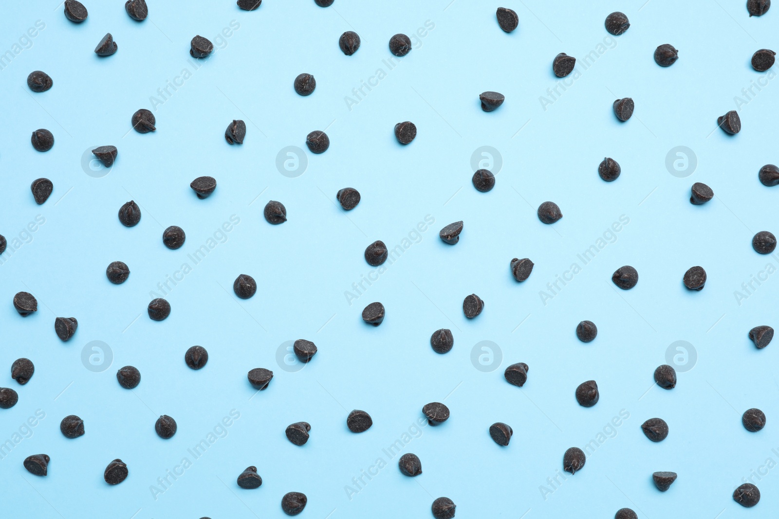 Photo of Delicious dark chocolate chips on light blue background, top view