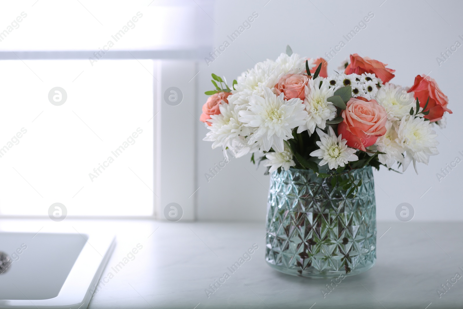 Photo of Vase with beautiful flowers on countertop in kitchen, space for text. Interior design