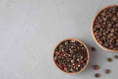 Photo of Different peppercorns on light grey table, flat lay. Space for text