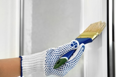 Woman painting window frame at home, closeup