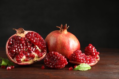 Photo of Fresh pomegranates and green leaves on wooden table