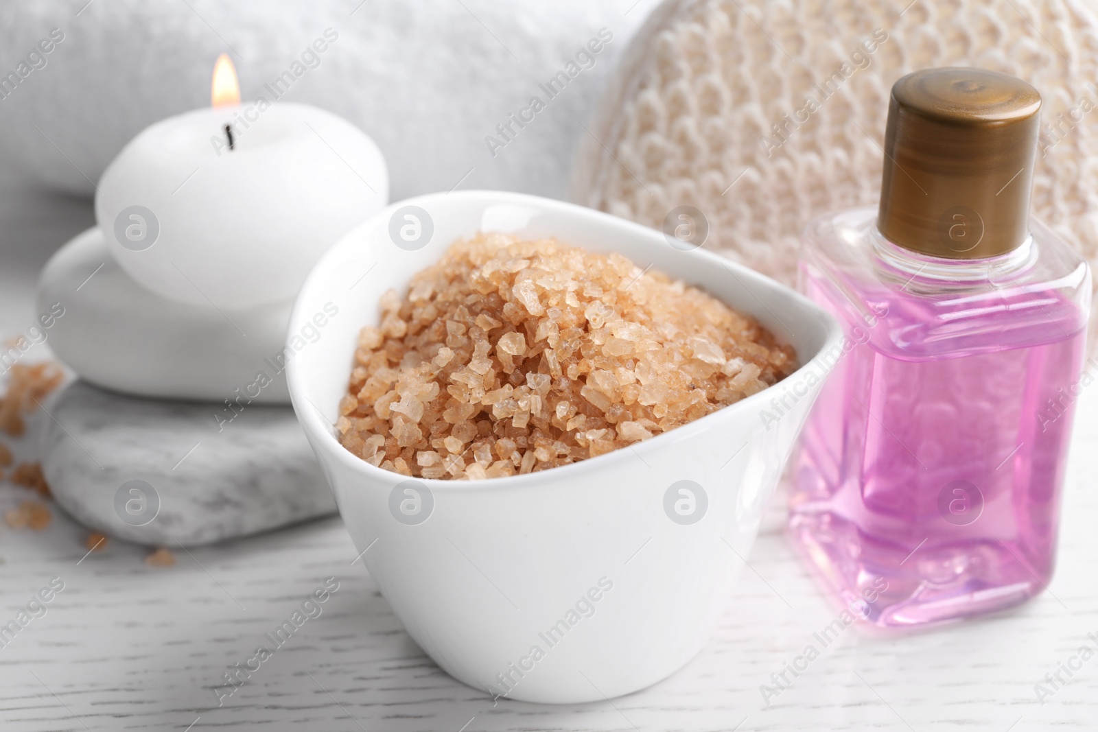 Photo of Salt and supplies for spa scrubbing procedure on white wooden table