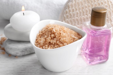 Salt and supplies for spa scrubbing procedure on white wooden table