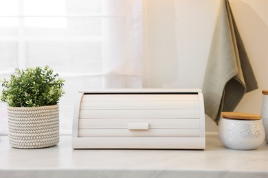 Wooden bread box and decorative elements on white countertop in kitchen