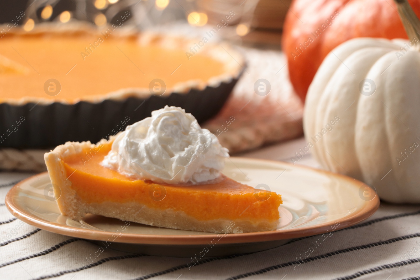 Photo of Piece of fresh homemade pumpkin pie with whipped cream on table