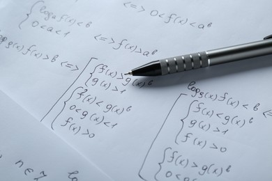 Sheets of paper with different mathematical formulas and pen, closeup