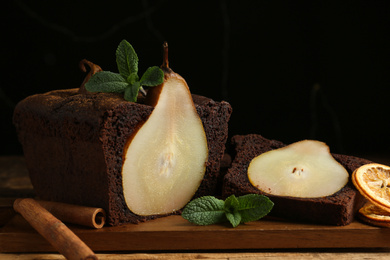 Photo of Tasty pear bread with mint, cinnamon and dried orange slices on wooden table, closeup. Homemade cake