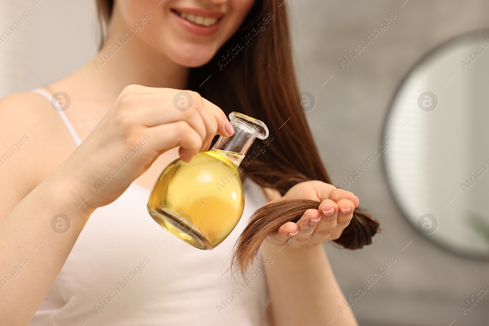 Photo of Woman applying oil hair mask at home, closeup